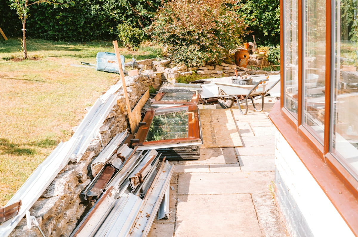 Sunny patio with stacked materials and cold frames