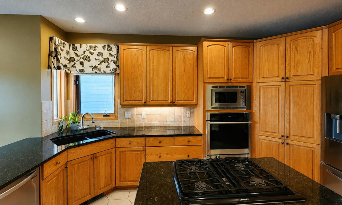 A kitchen with oak cabinets, black granite countertops, and a central gas cooktop